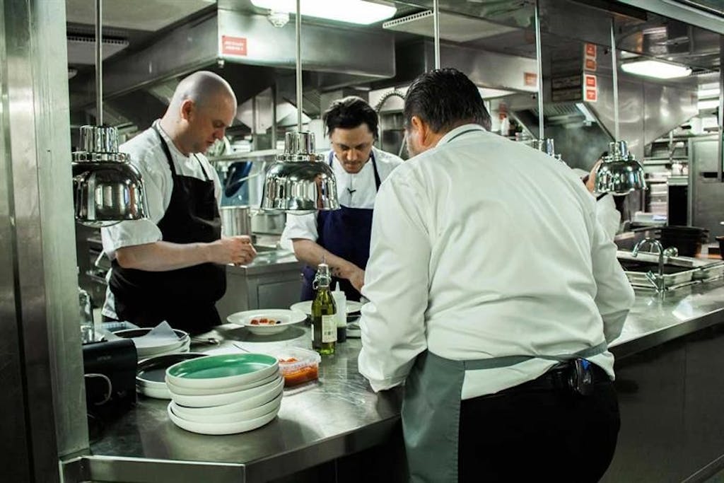 Christian Mortensen (til venstre) og Søren Westh (i midten) gør forretten dansk kongekrabbe klar. Tjeneren Benny står klar.