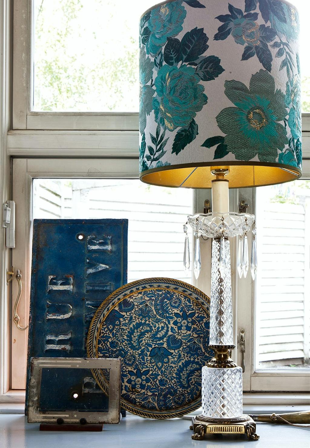 Vindueskarm med lampe i krystal, fransk vejskilt og andre pyntegenstande