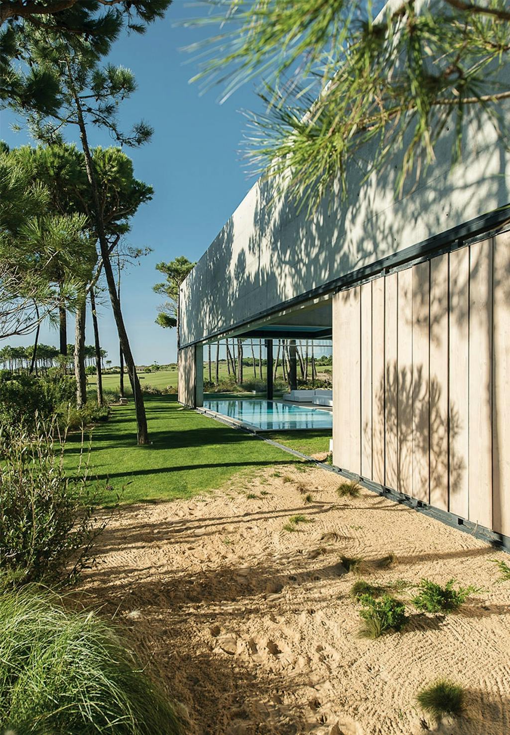 Have med træer, græsplæne, sand og adgang til swimmingpool