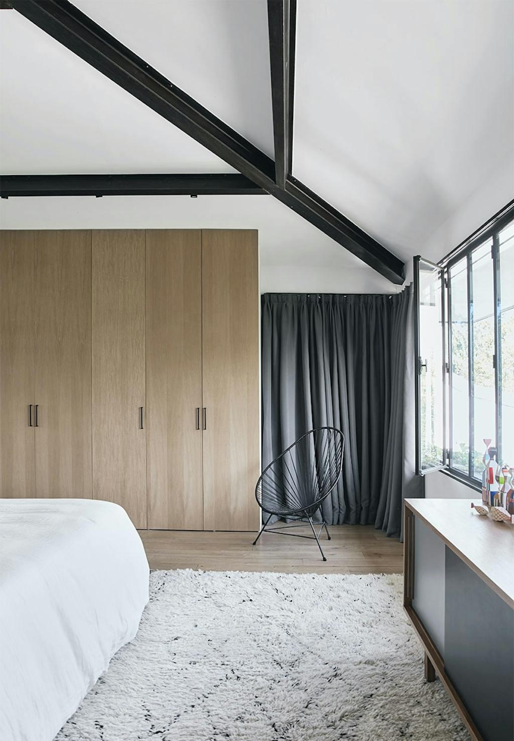 Soveværelse hvor endevæg er garderobeskabe i egetræ, med gulvtæppe fra Marokko og skænk fra 50'erne