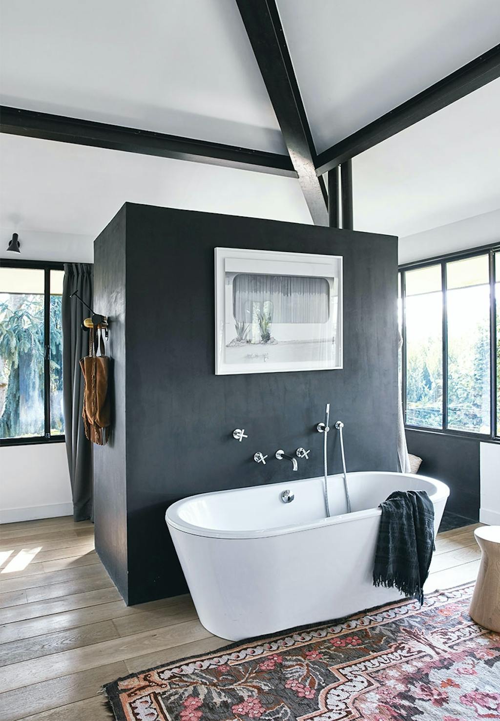 Stort badeværelse med hvidt badekar og en sort boks der gemmer brusekabinen