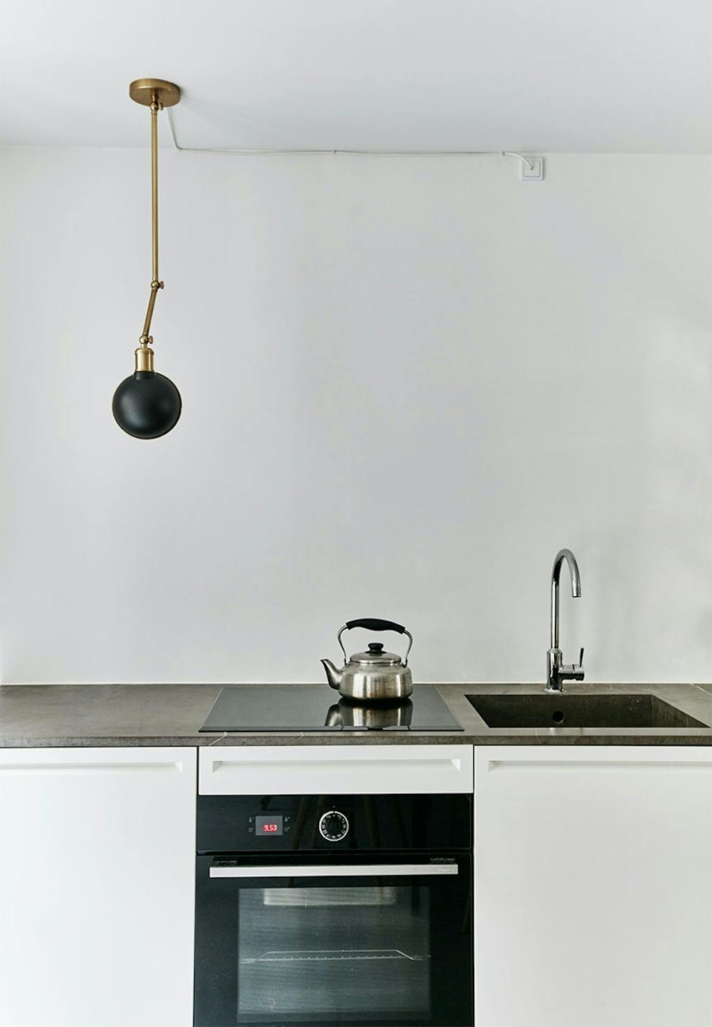 Enkel, skulpturel lampe af Søren Rose hængende over køkkenbordet 