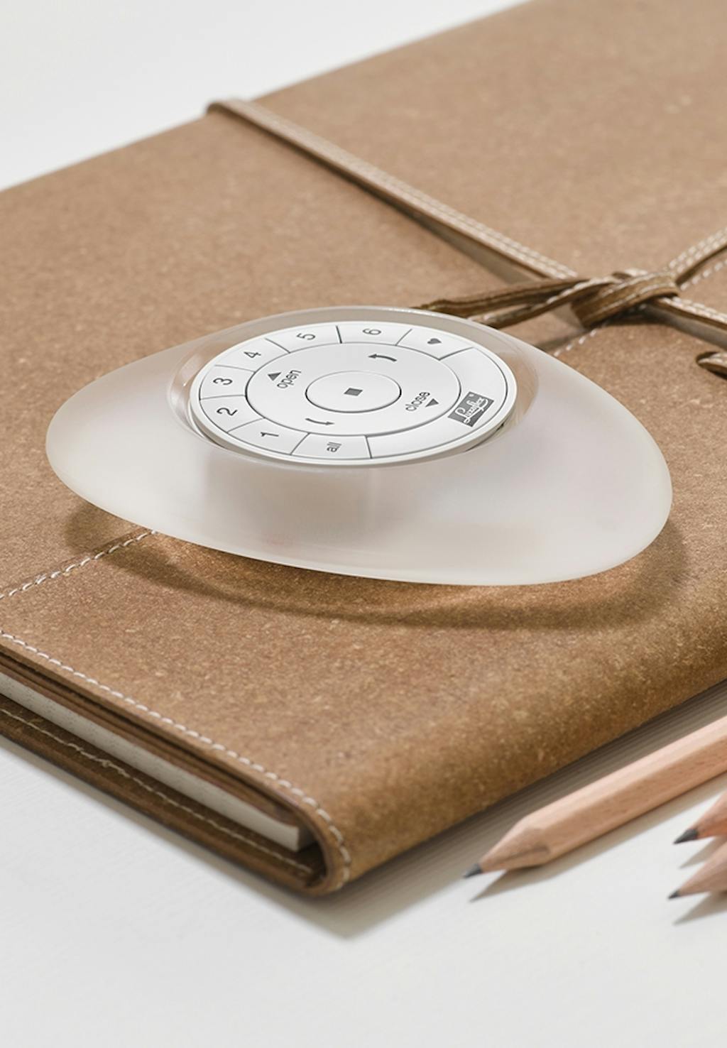 Fjernbetjening til intelligent gardinstyring oven på brun notesbog