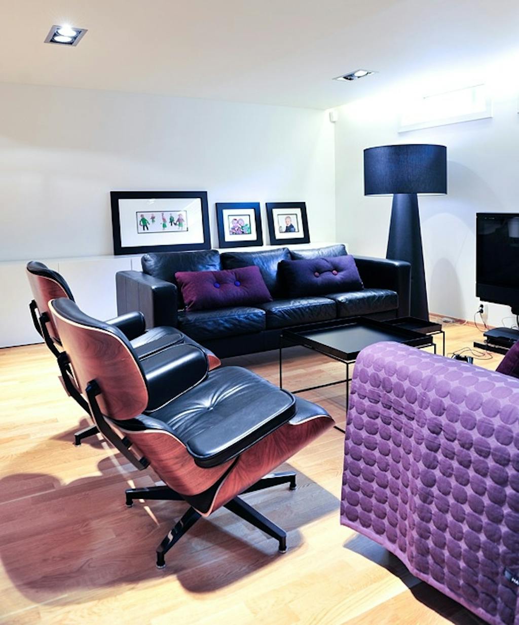 To skinnsofaer fra Ikea får selskap av to Eames loungestoler rundt bordene fra Hay. De lilla putene og teppet er også fra Hay.