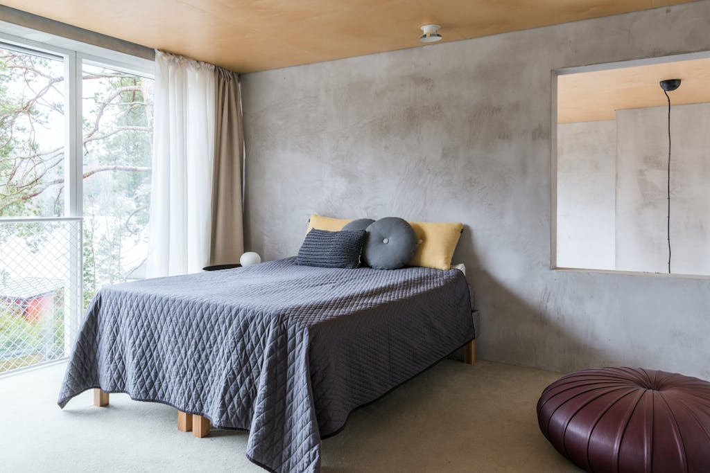 Minimalistisk møblert soverom med betongvegg