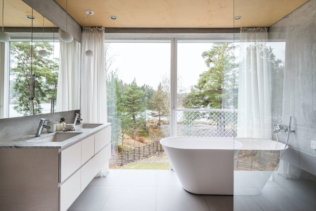 Bad med vindusvegg og detaljer i marmor, tre og betong.