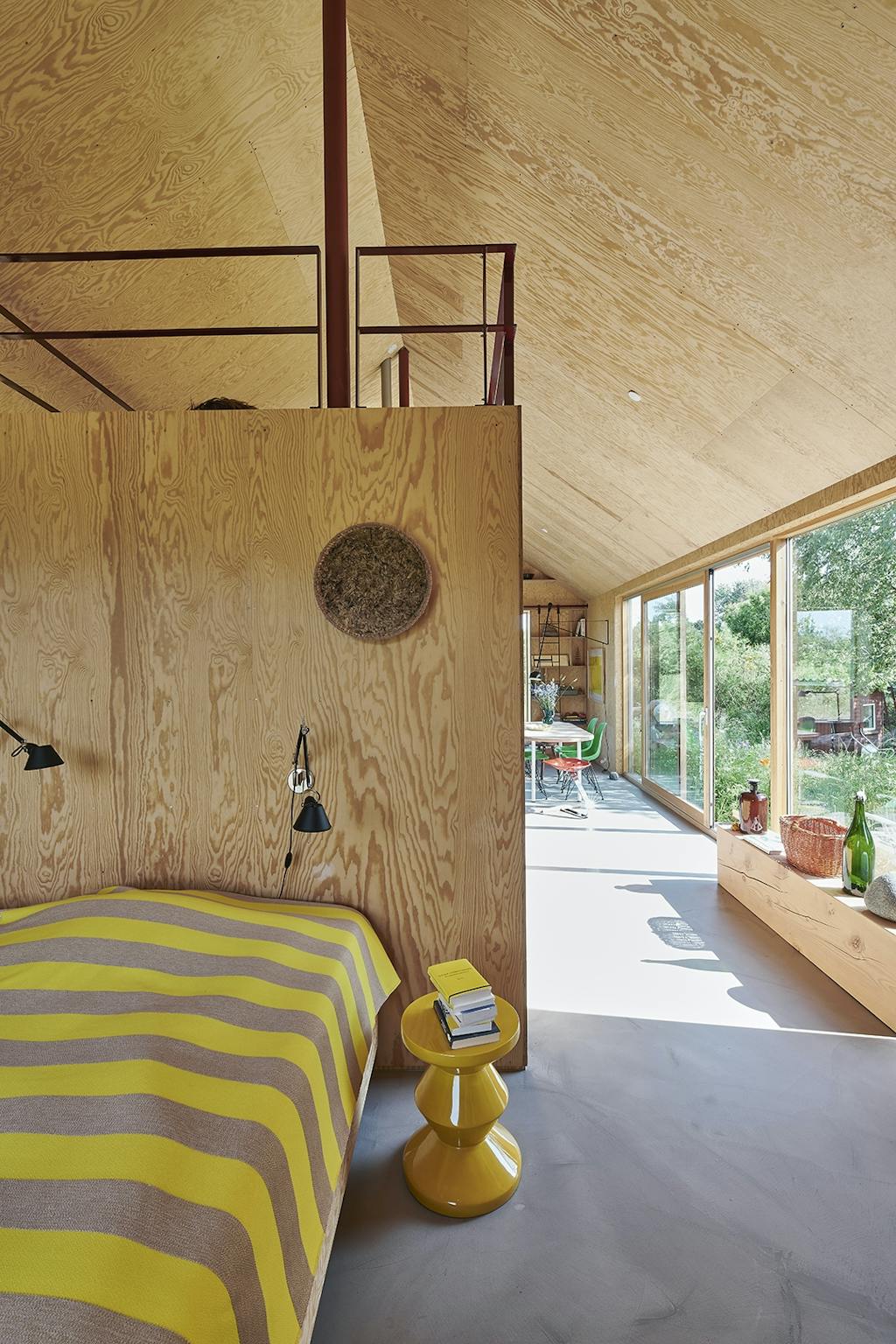 Soveværelse med vægge i krydsfiner og gult sengetæppe