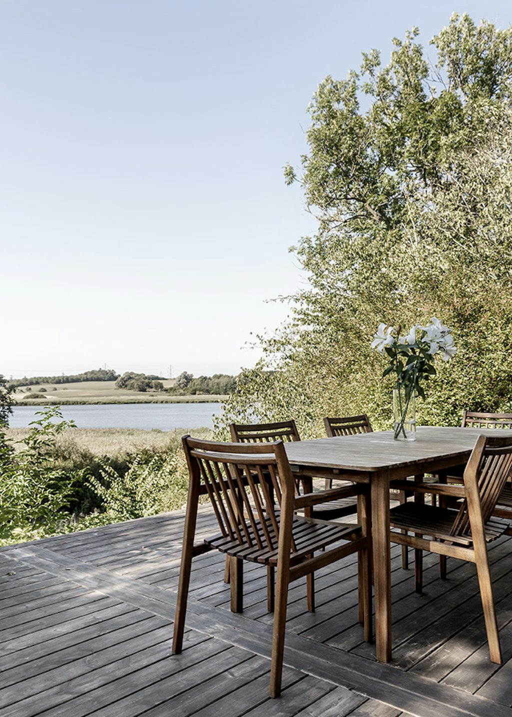 Terrasse med havemøbler og udsigt til en sø Terrasse med havemøbler og udsigt til en sø