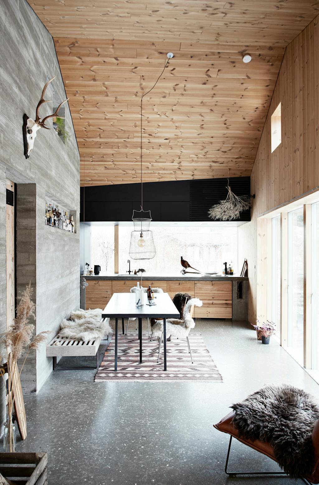 eetkamer in houten hut met betonnen muren en natuurlijke materialen
