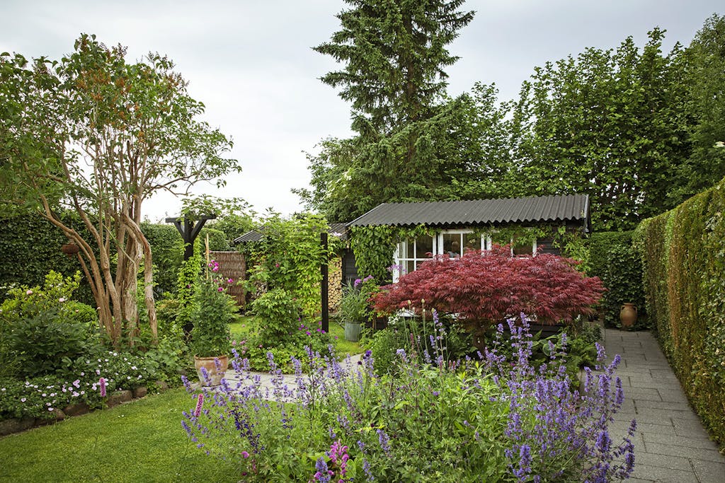 Have med flisesti og farvekoordinerede bede Have med flisesti og farvekoordinerede bede