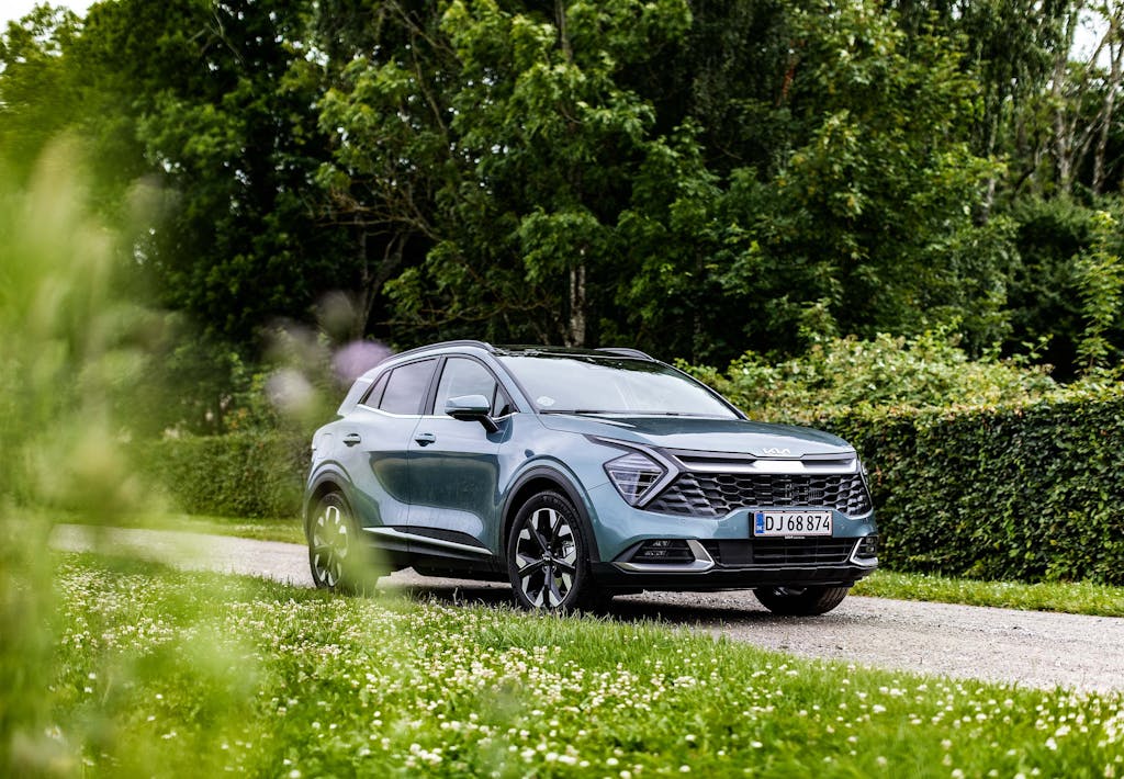 Kia Sportage på grusvej med grønne hække