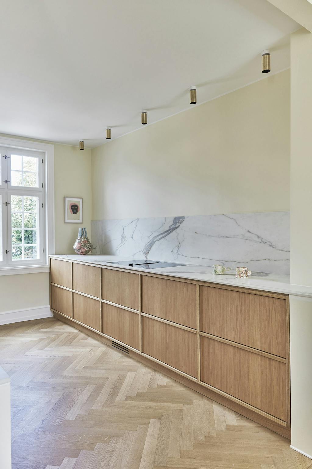 Køkken i træ med marmor backsplash og sildebensgulve