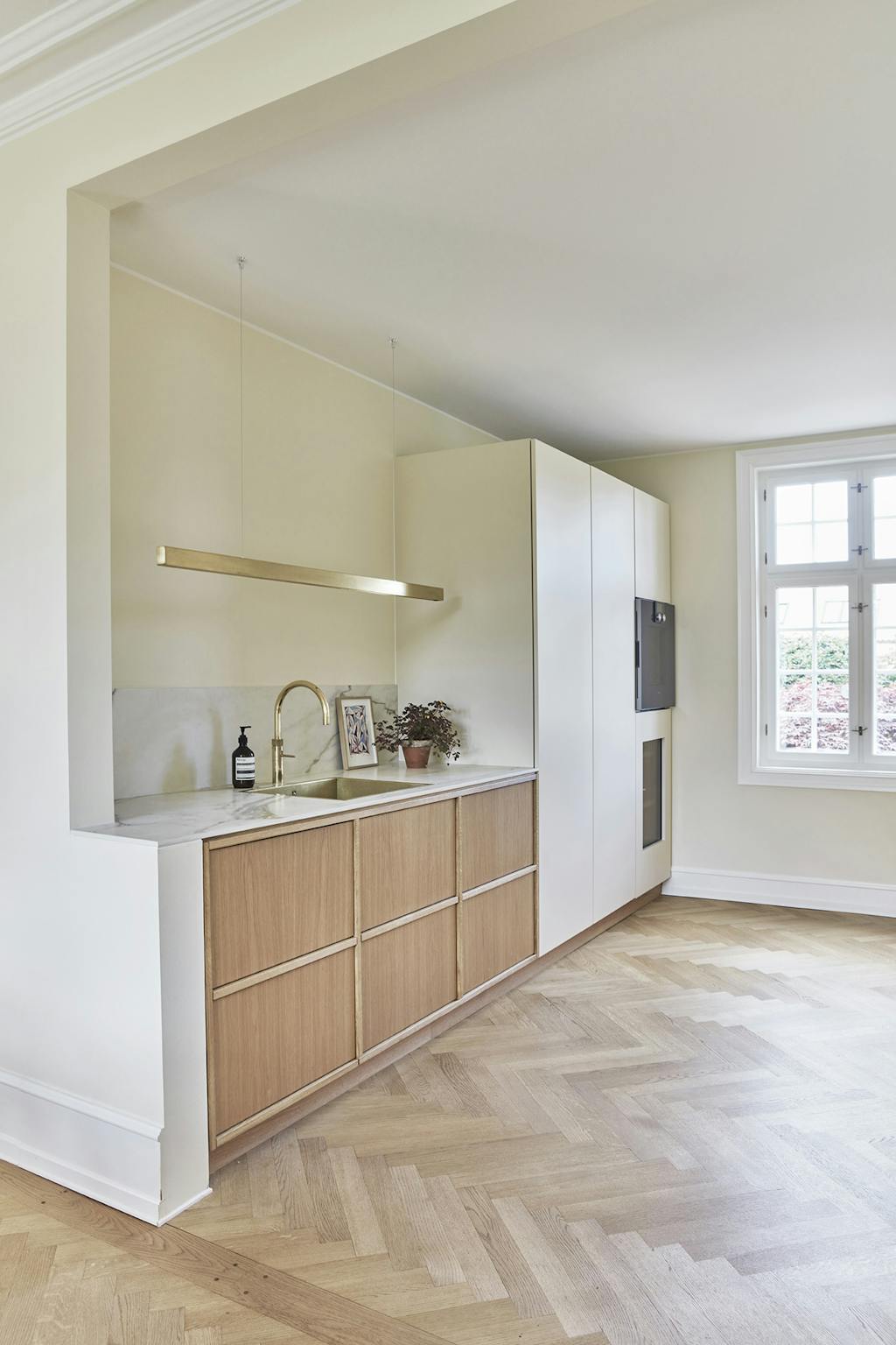 Køkken i træ med messinglampe og sildebensgulve