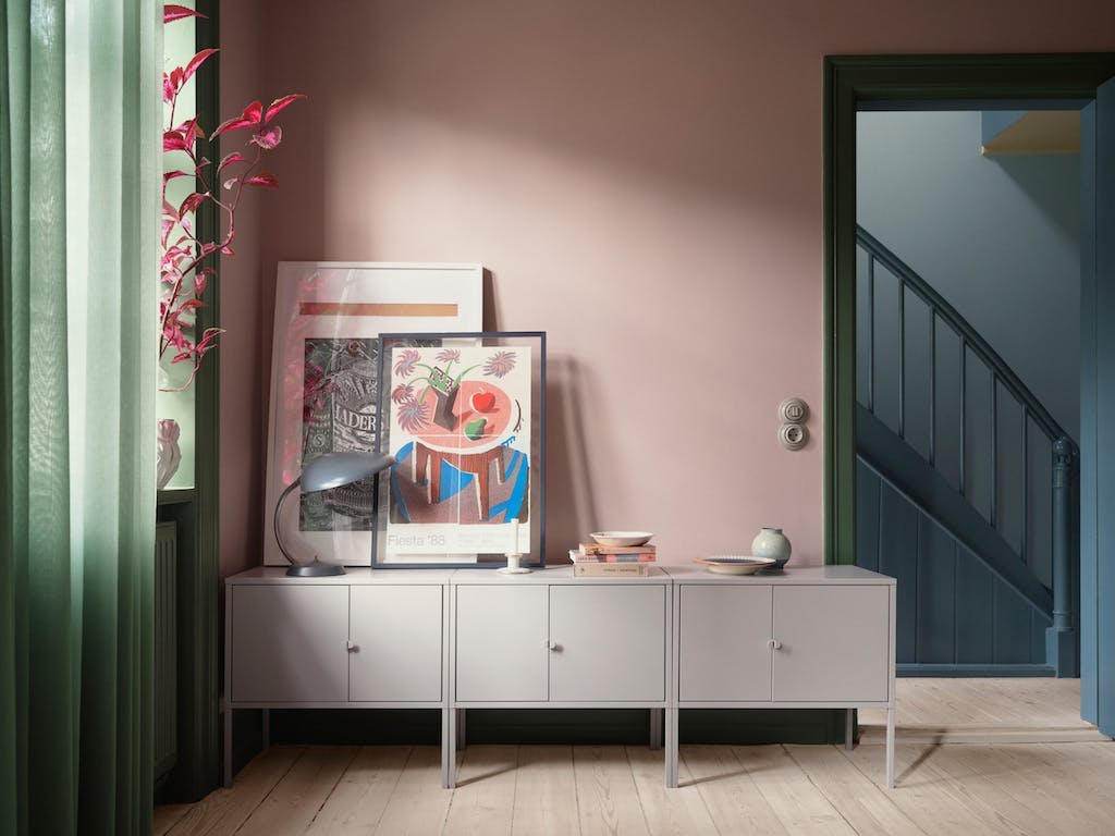 Roze/groene woonkamer met doorkijkje naar blauw trappenhuis