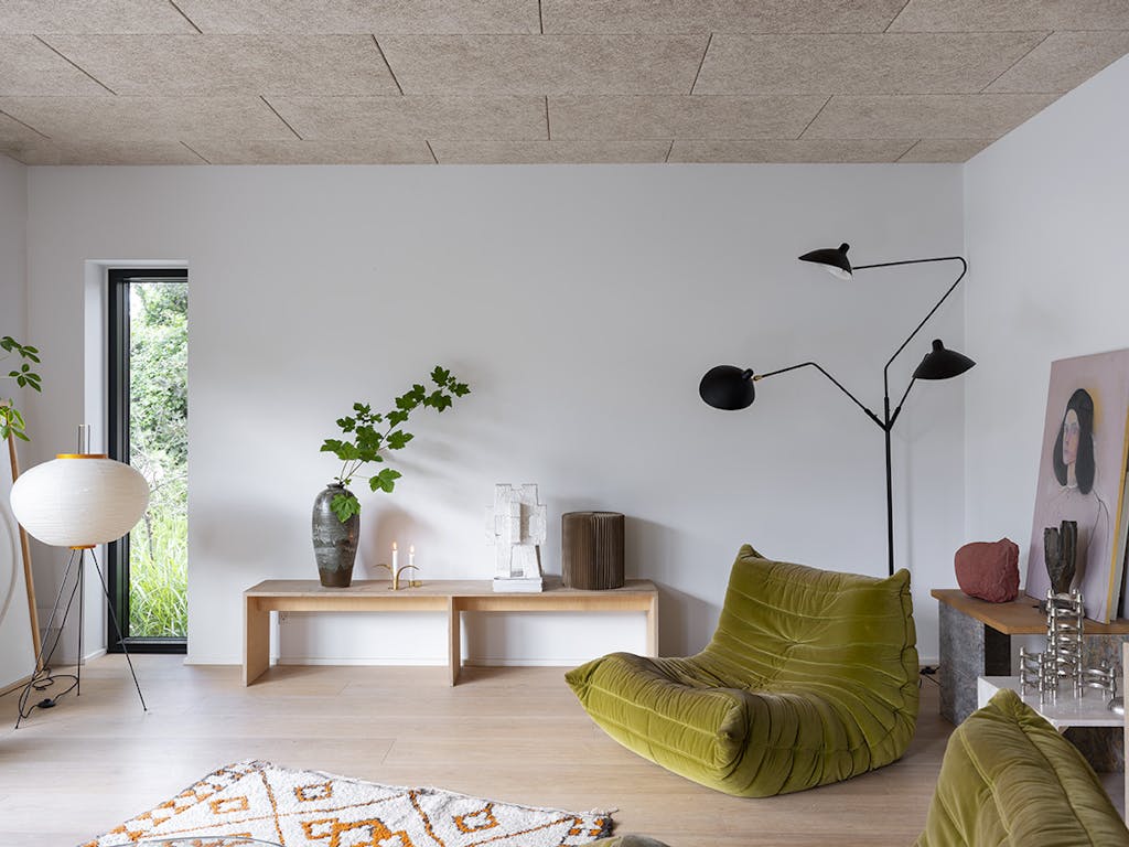 Indretning i stue med grøn loungestol og akustiklofter