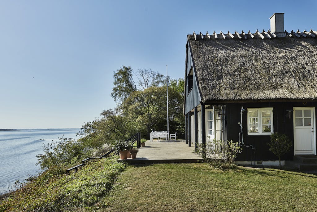 Idyllisk sort sommerhus med stråtag udsigt over Isefjorden