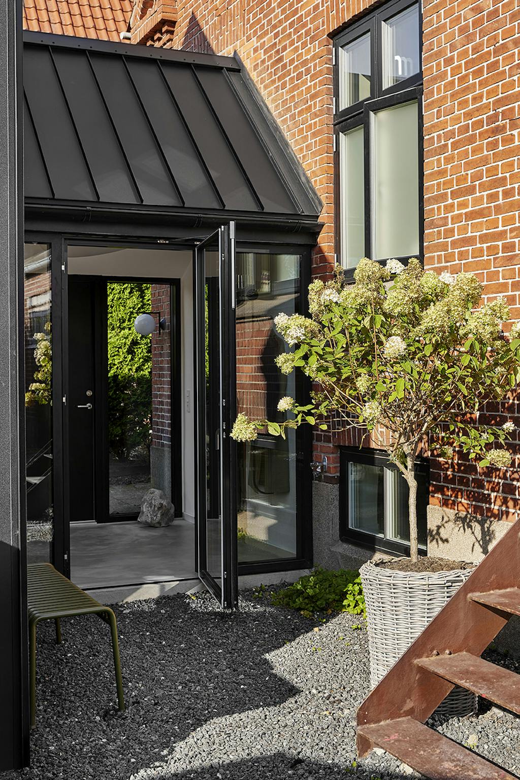 Rød murermestervilla med moderne tilbygning.