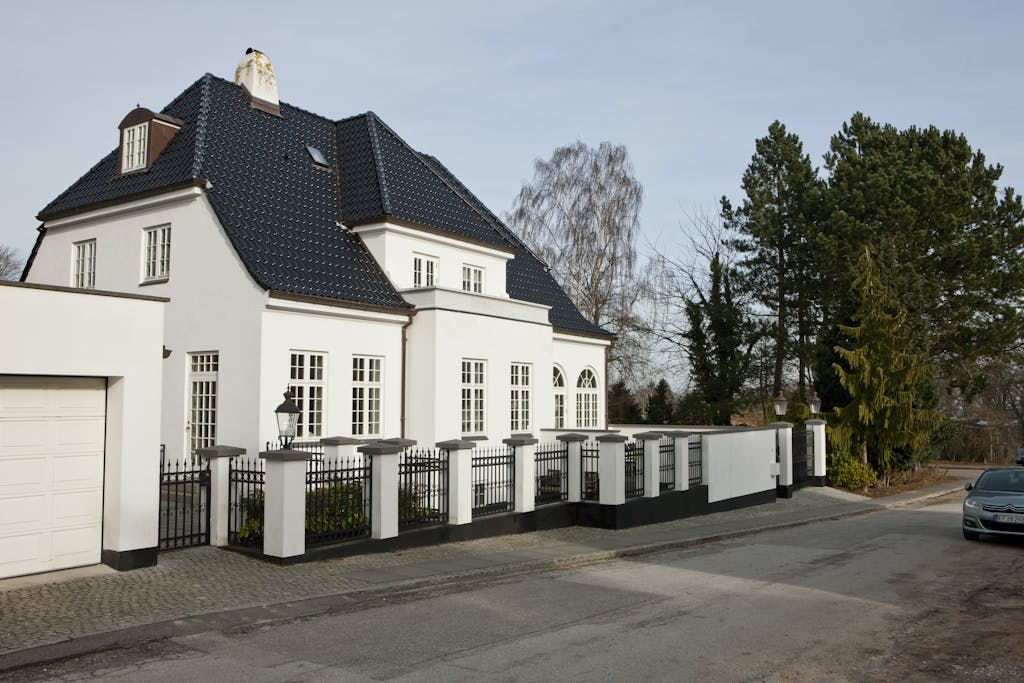 Patriciervilla udefra. Hvidpudset og sortglaseret tegltag