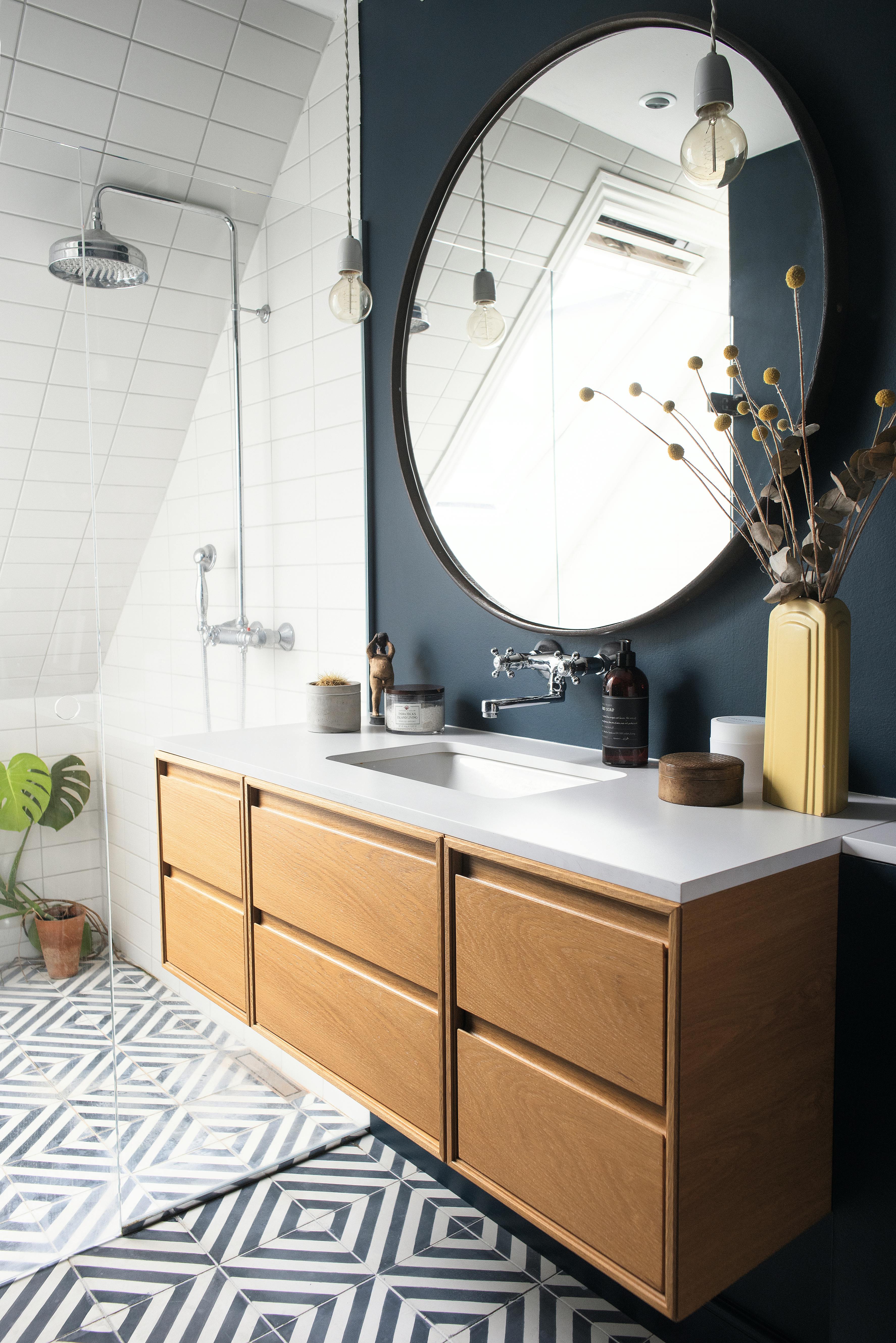 Badeværelse med rundt spejl og mørkeblå væg 