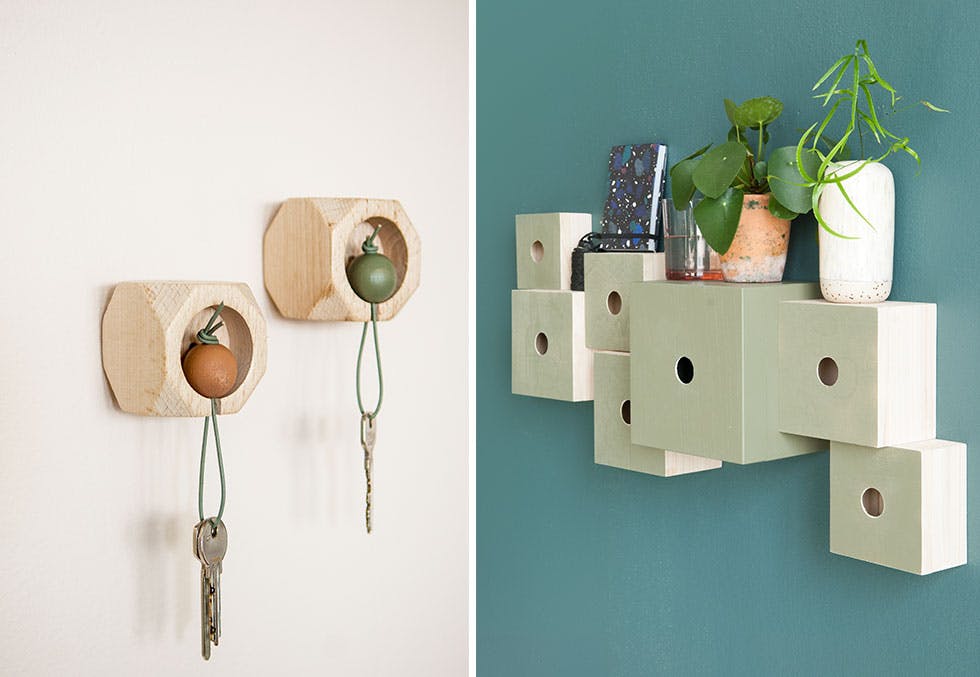 Nøkkelhus i tre laget av trekuler og telysholdere. Trekasser med hull gjennom på mørkegrønn vegg. 