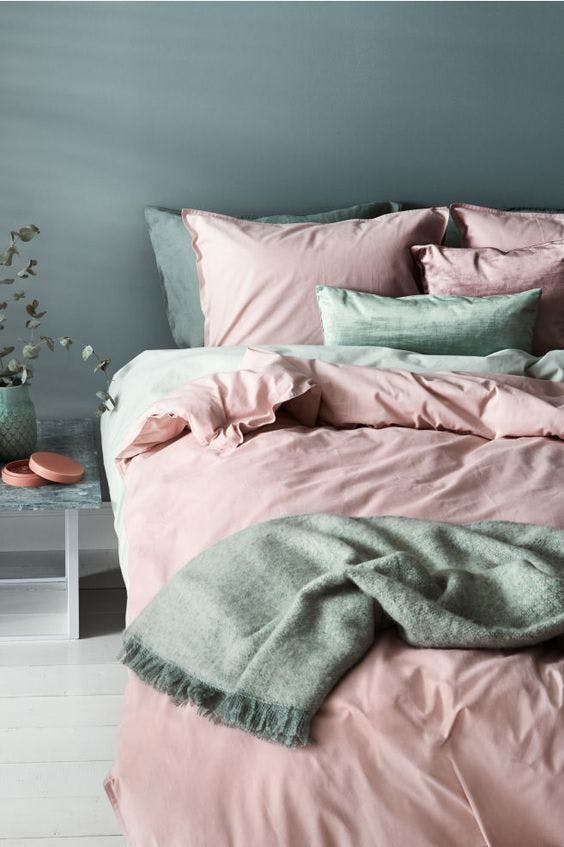 teppe i mint på en rosa seng med grå vegger