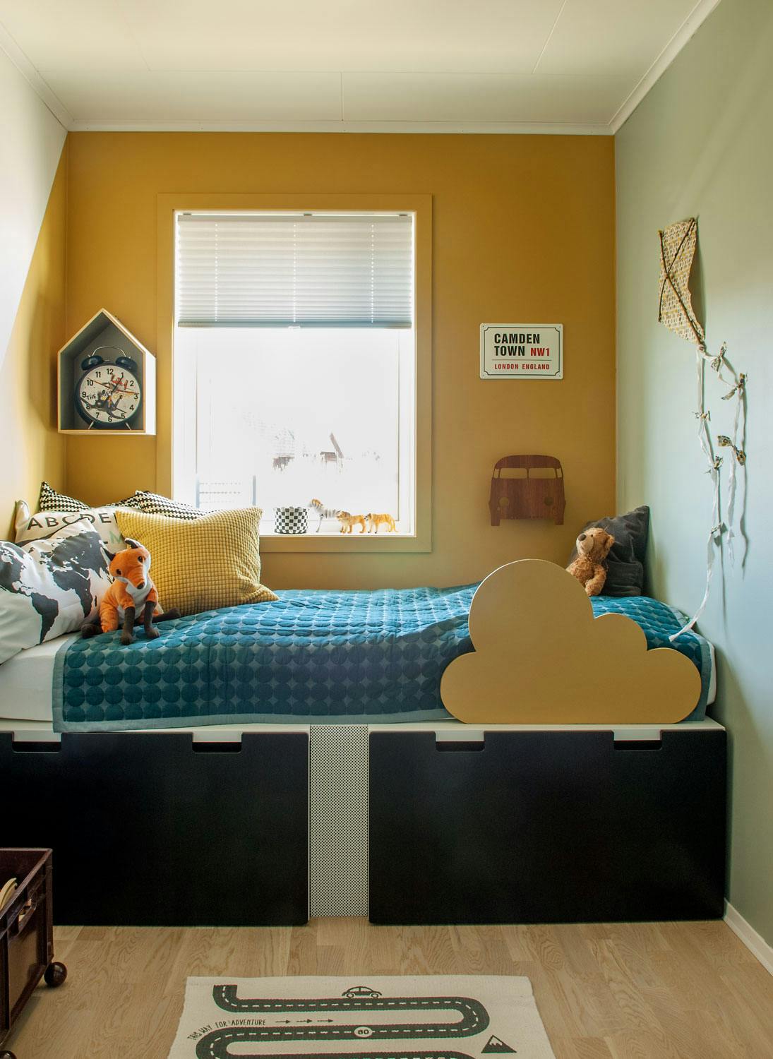 Sengen til Emiliam består av en madrass lagt oppå Stuva-skuffer fra Ikea. Vegghyllen er fra Bloomingville, bilteppet er fra Oyoy, og sengeteppet er fra Hay.