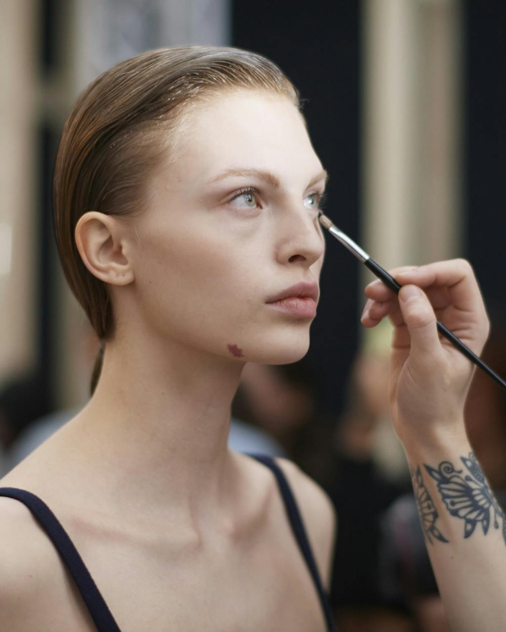 modell blir sminket med concealer under øyet