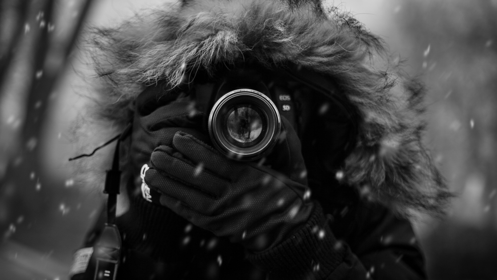 Fotograf fotograferar med fullformatskamera på vintern i snöväder