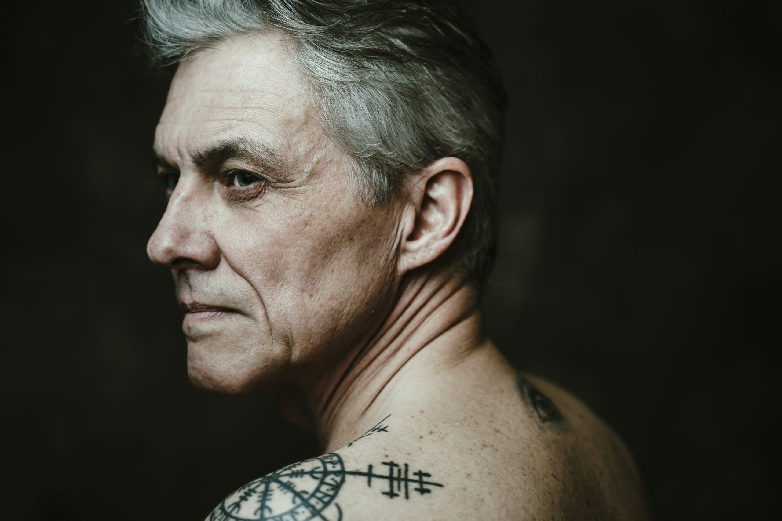 Kahden studiosalaman valaisema mies katsoo ulos kuvan vasemmalla puolella