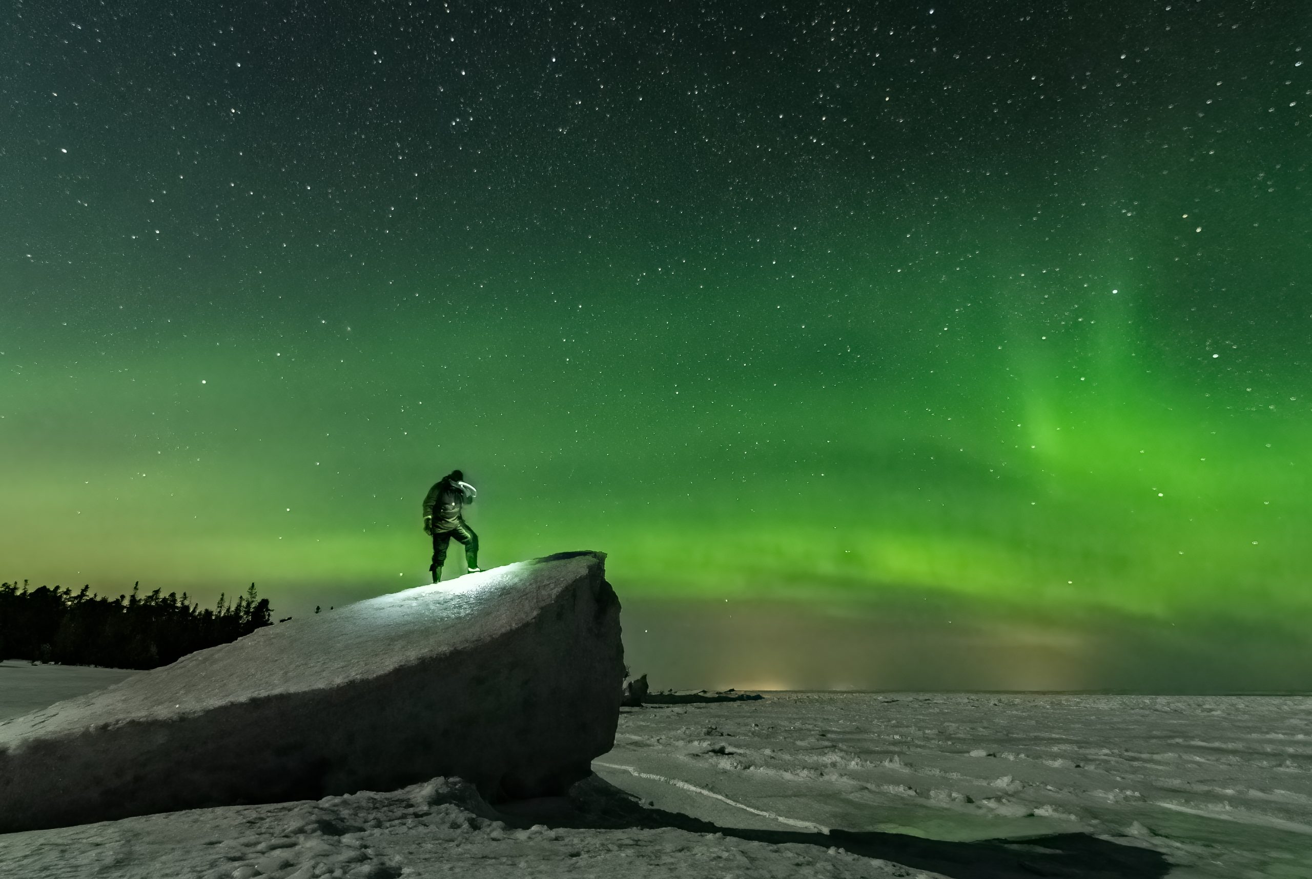 Nordlys i Nordsverige med mand på sten
