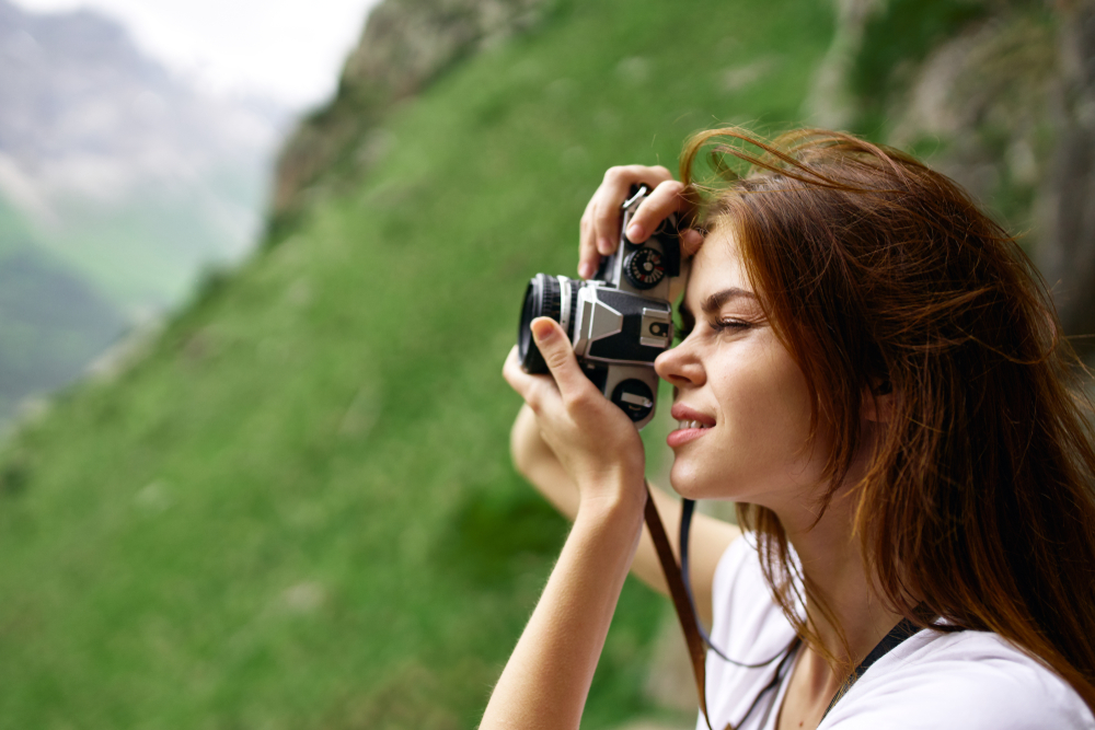 Kvinde fokuserer manuelt på analogkamera på en tur i bjergene