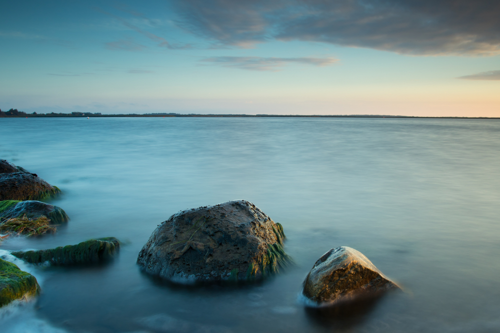 Vatten vid stranden slätas ut med lång slutartid 