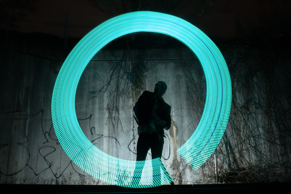 Man fotograferad med lång slutartid som målar med ljus för att skapa intressant foto