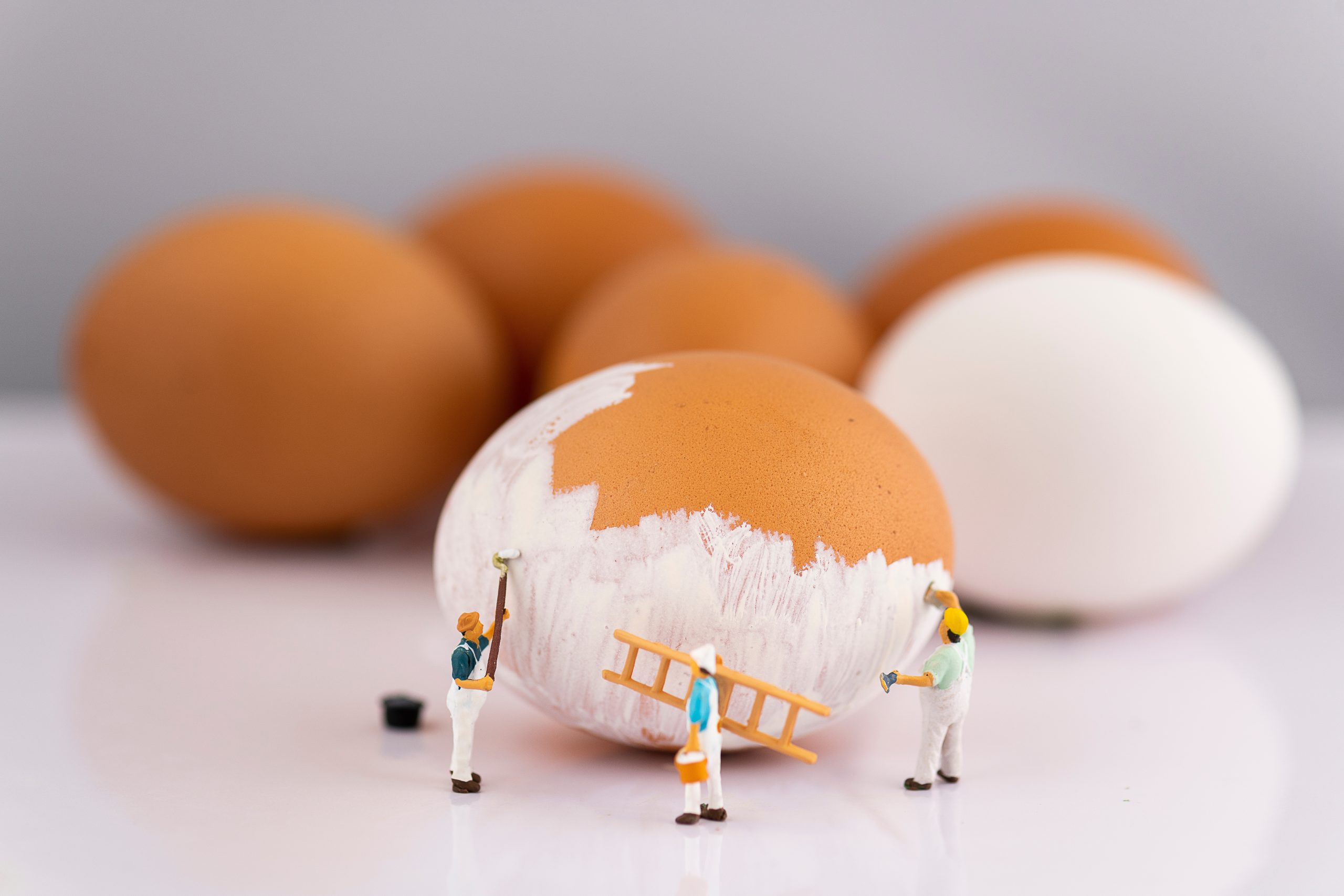 Små figurer målar stort ägg.