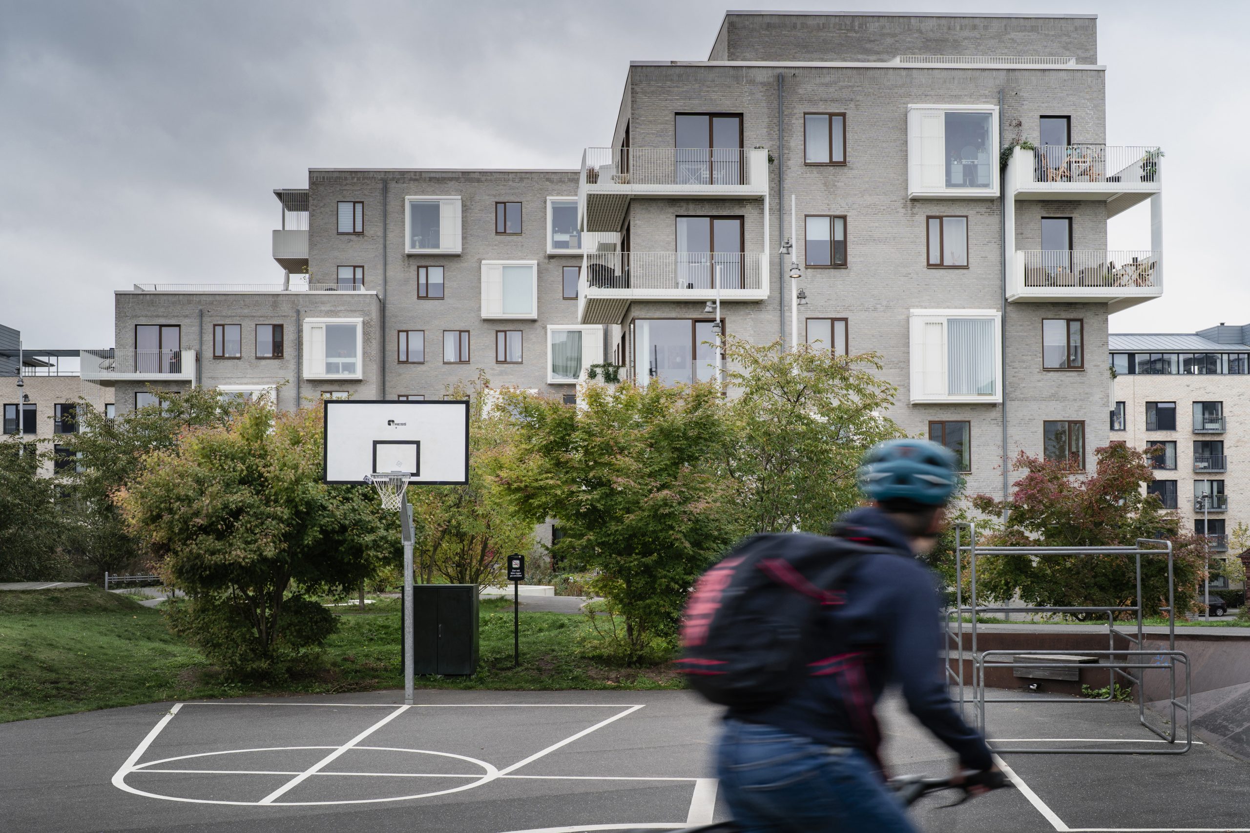 Pojke cyklar förbi basketplan i hög fart