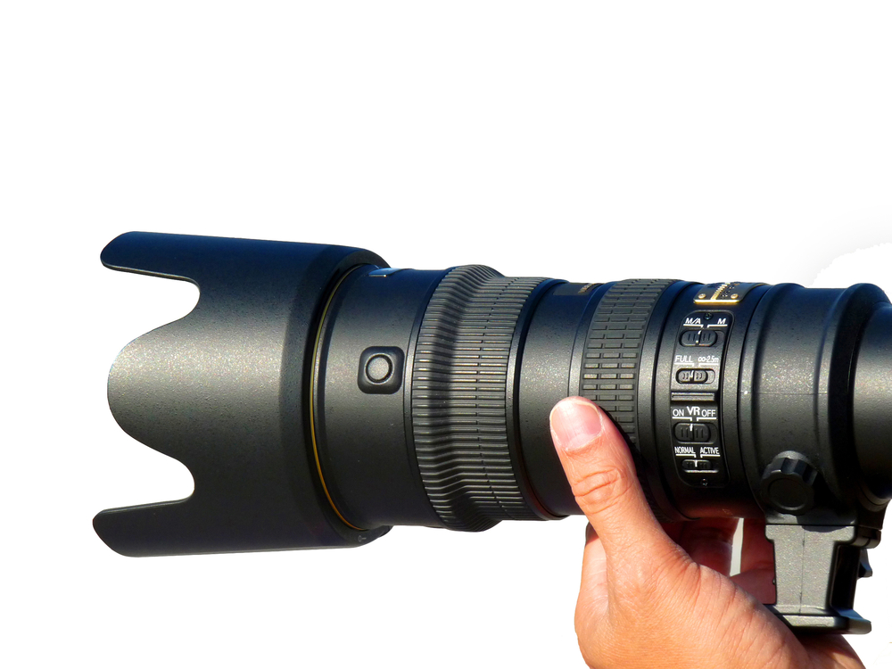 teleobjektiv med många knappar hålls upp i varmt ljus