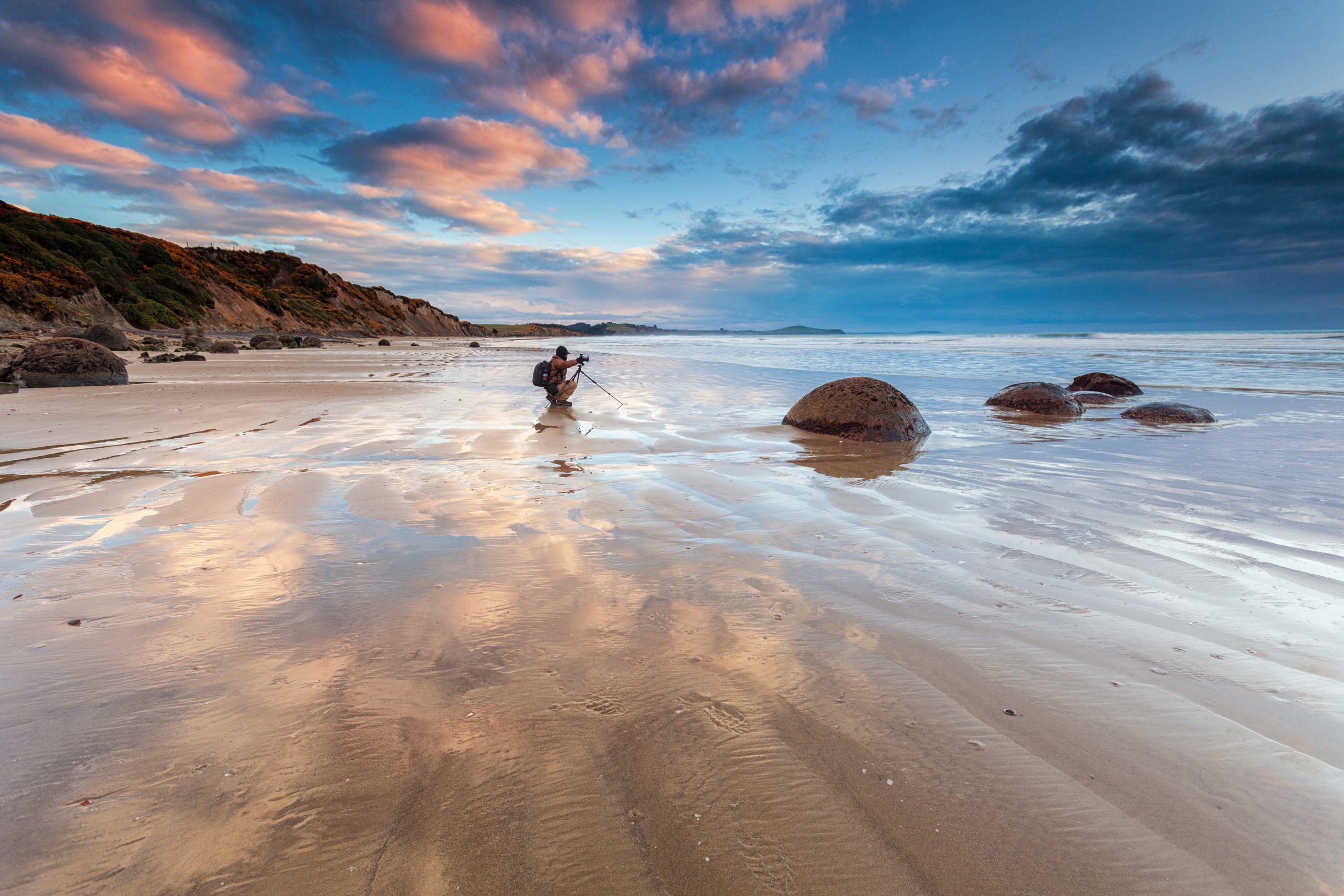 Mies kuvaa rannalla.