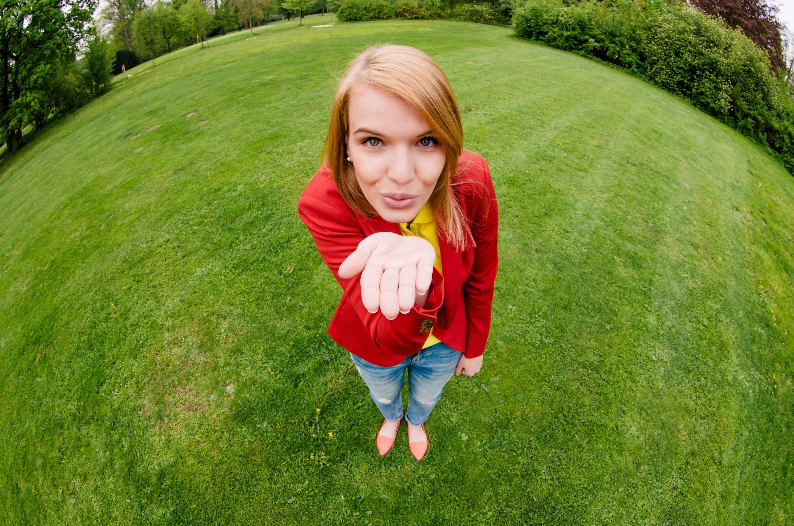 Kvinna i röd kavaj ger en slängkyss till fotografen genom ett fisheye-objektiv