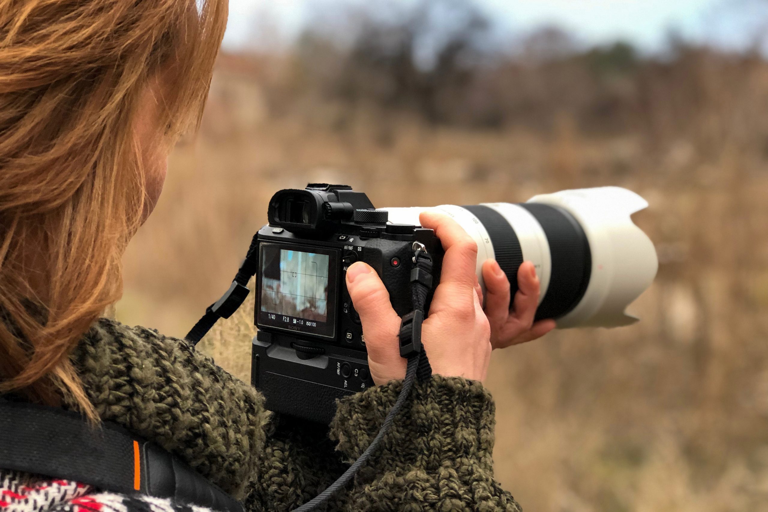 Nainen pitelee järjestelmäkameraa, jossa on 70–200 mm:n objektiivi