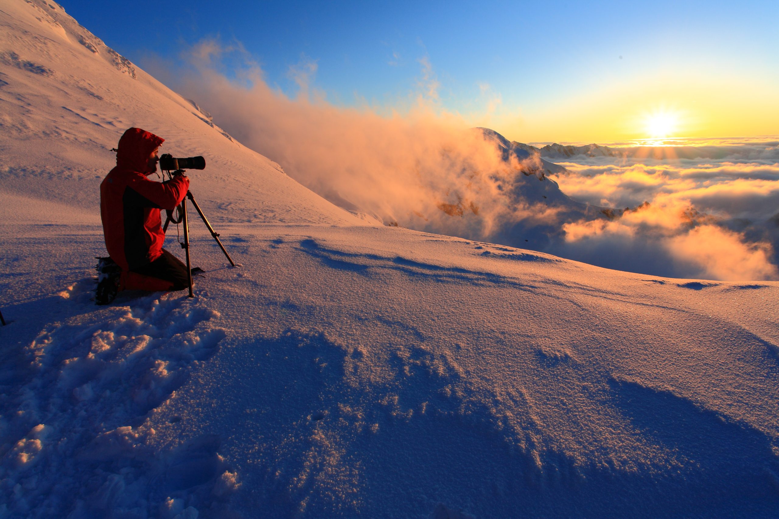 Mies kuvaa auringonnousua vuoristossa.