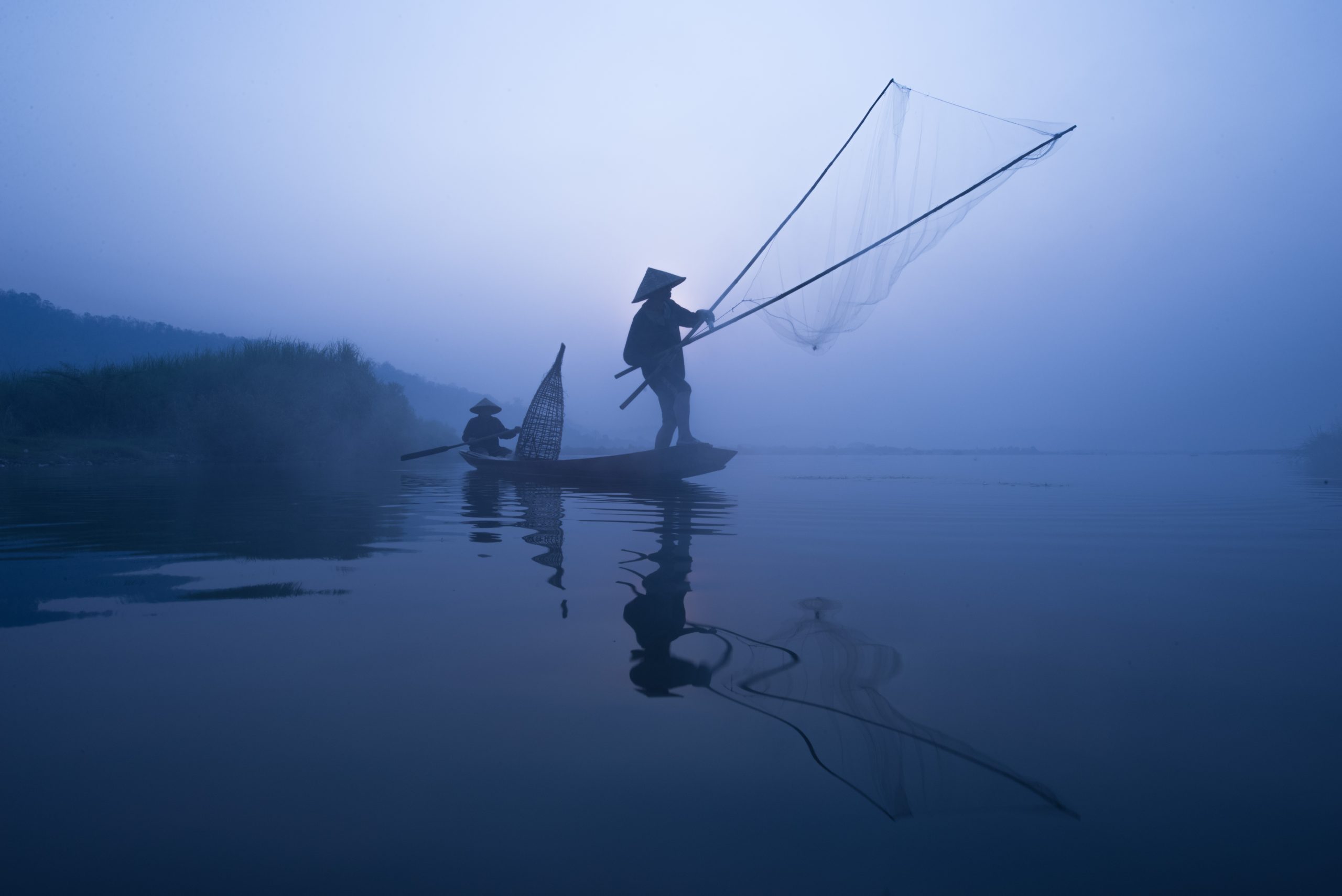 Kalastaja purjehtii veneellä verkkoineen