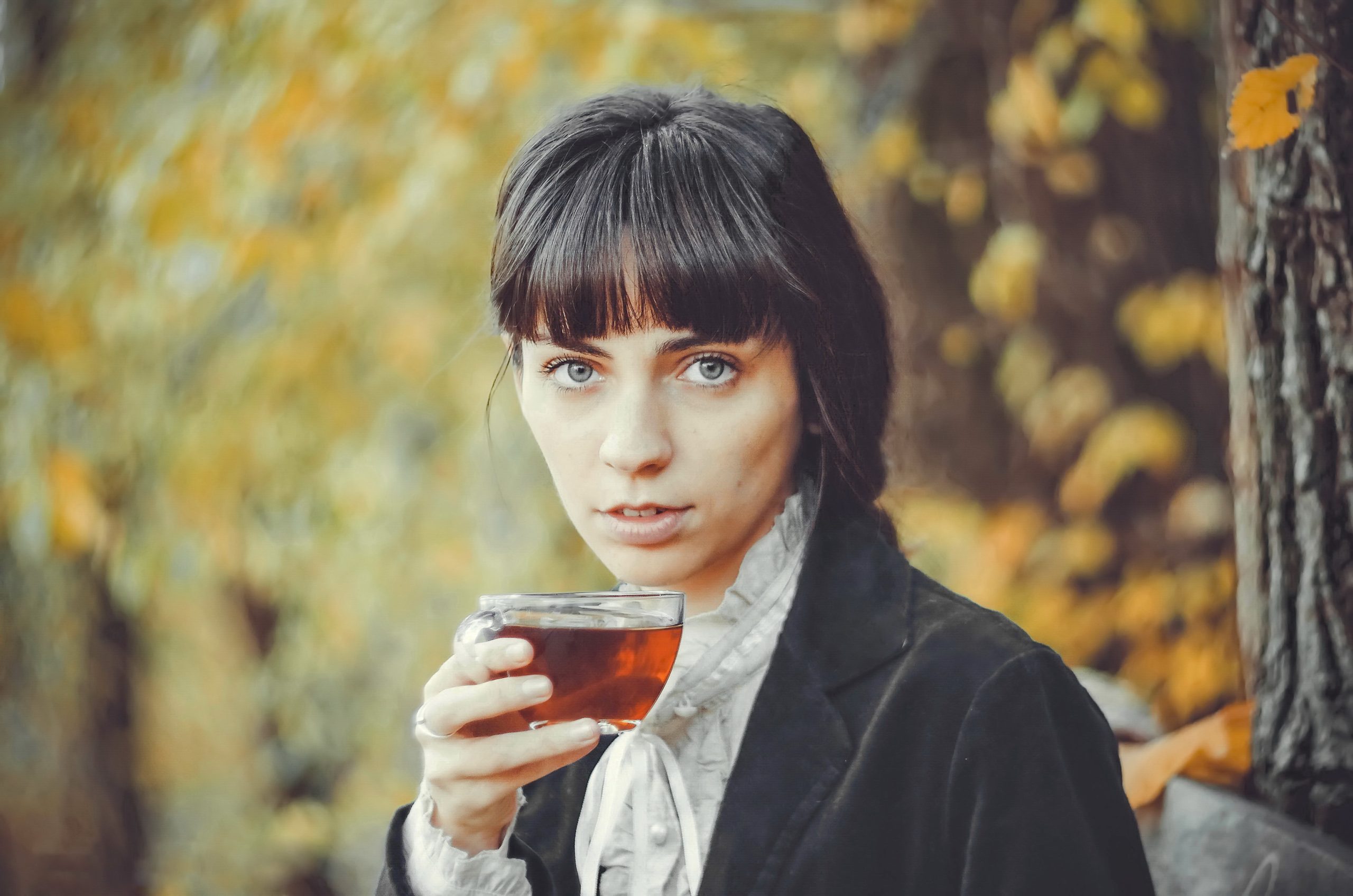 Nainen kuvattuna ulkona teellä entisajan vaatteissa