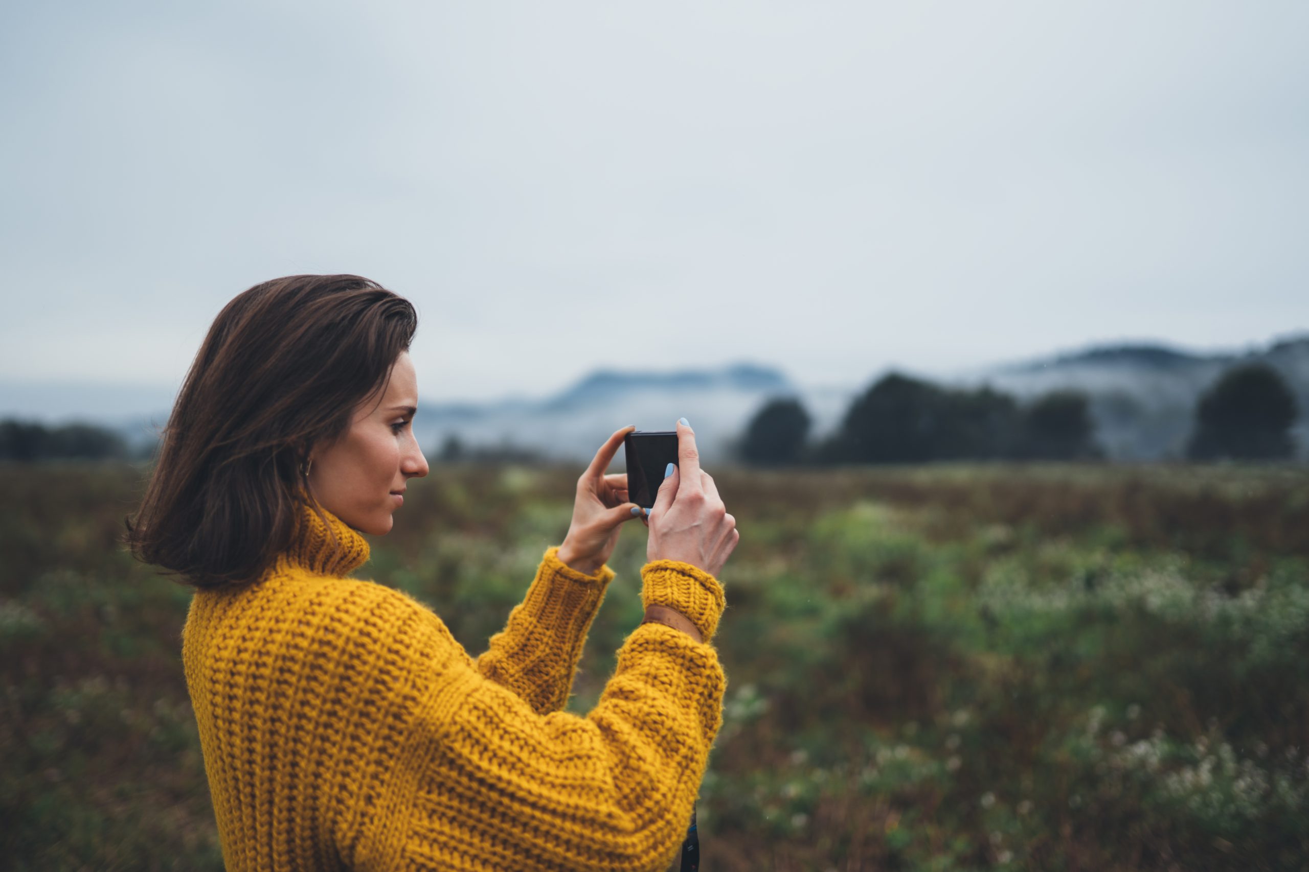 Kvinna fotograferar med mobilen.