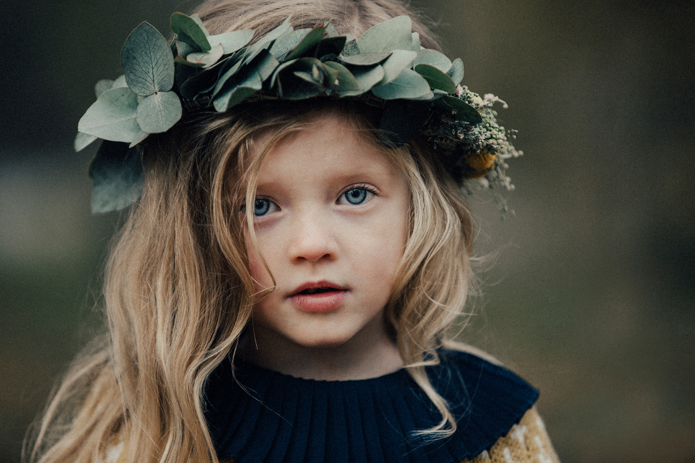 Porträttbild av ljushårig flicka med blomsterkrans