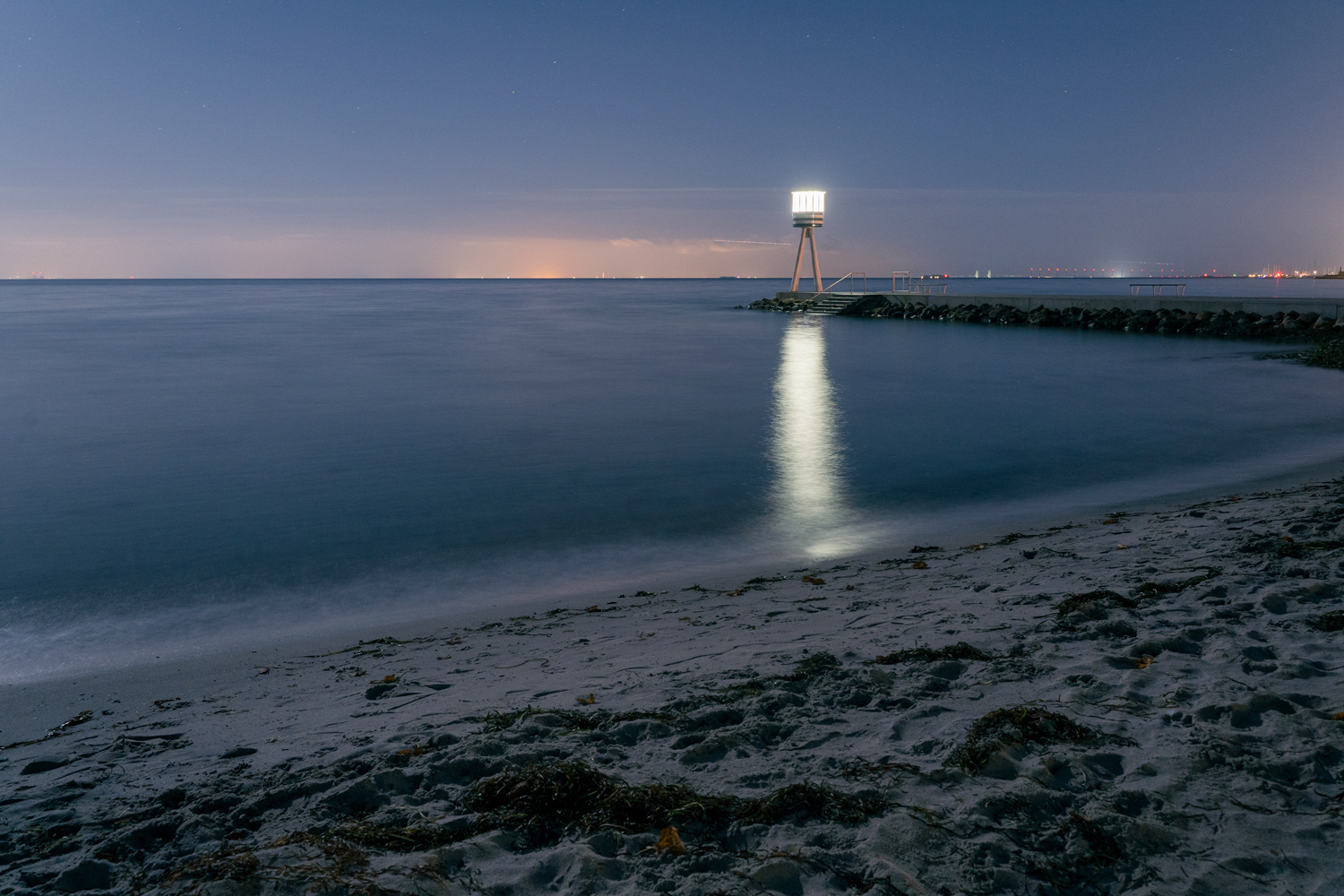 Bild av kustlinje och livräddartorn i fullmåne