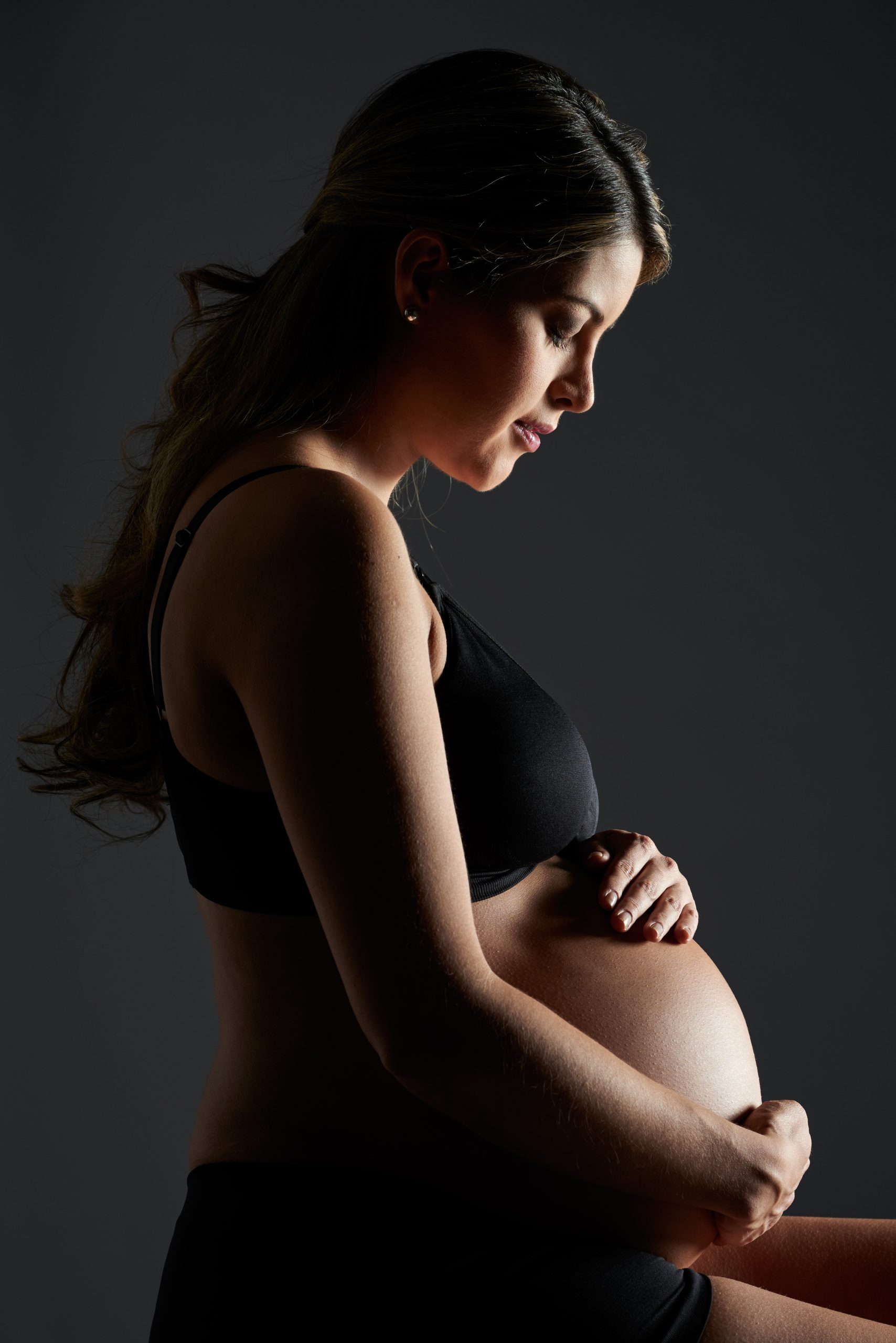 Foto av ung gravid kvinna mot mörk bakgrund