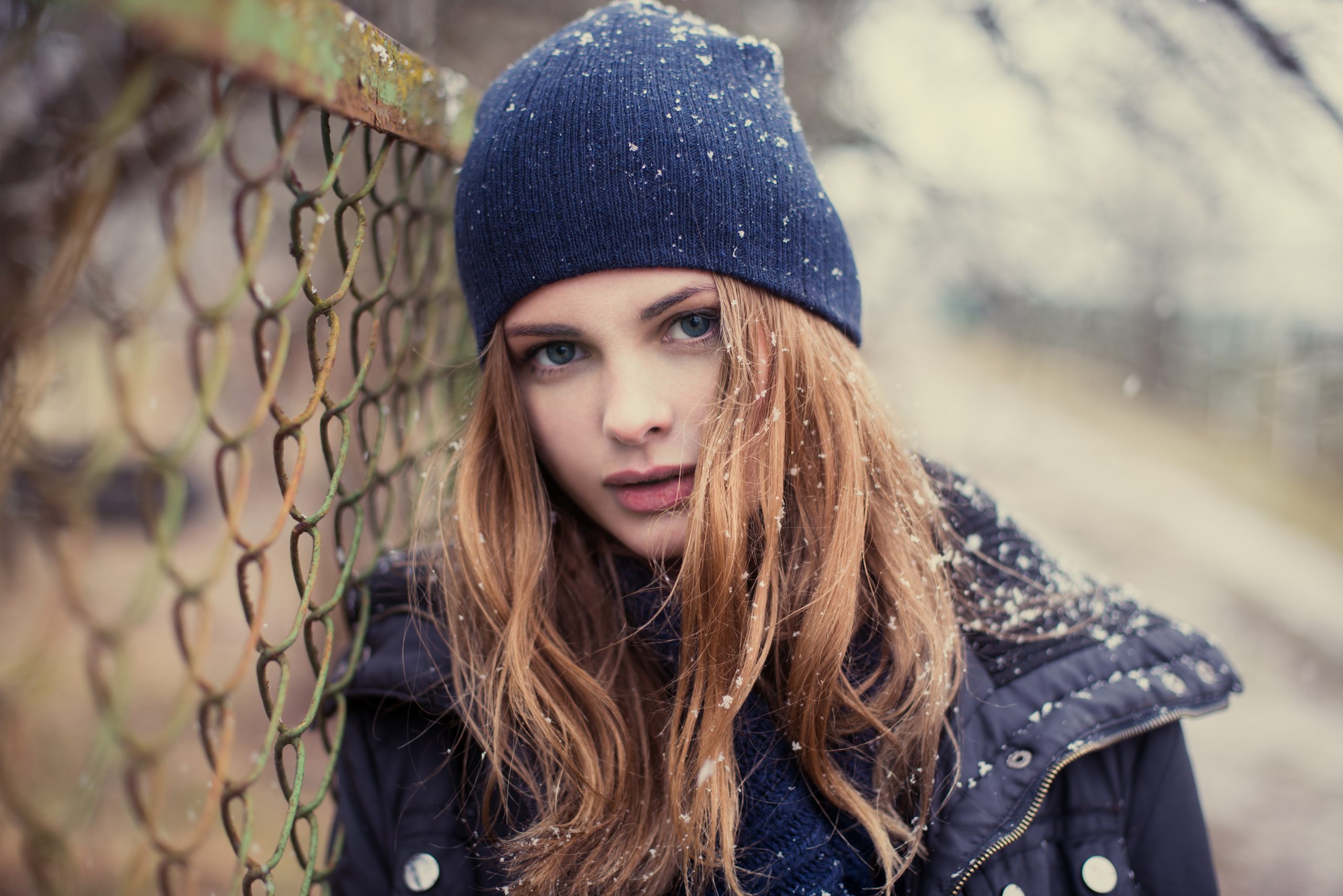 Ung kvinna med mössa och vinterjacka i snö