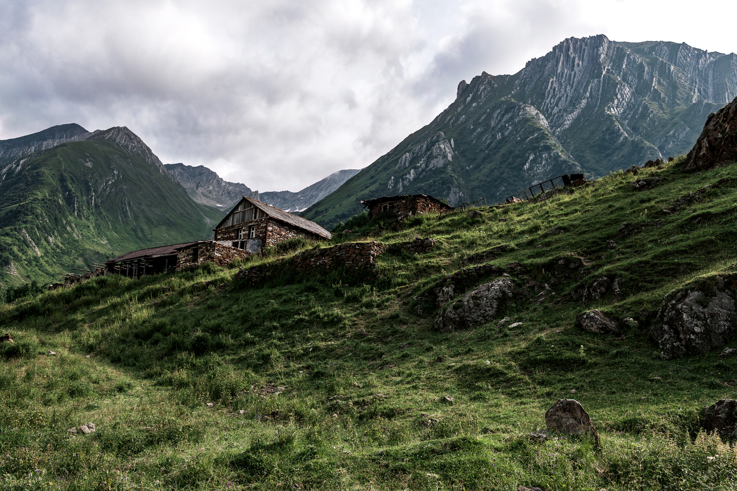 Gammelt hus fotograferet nedefra med bjerge i baggrunden