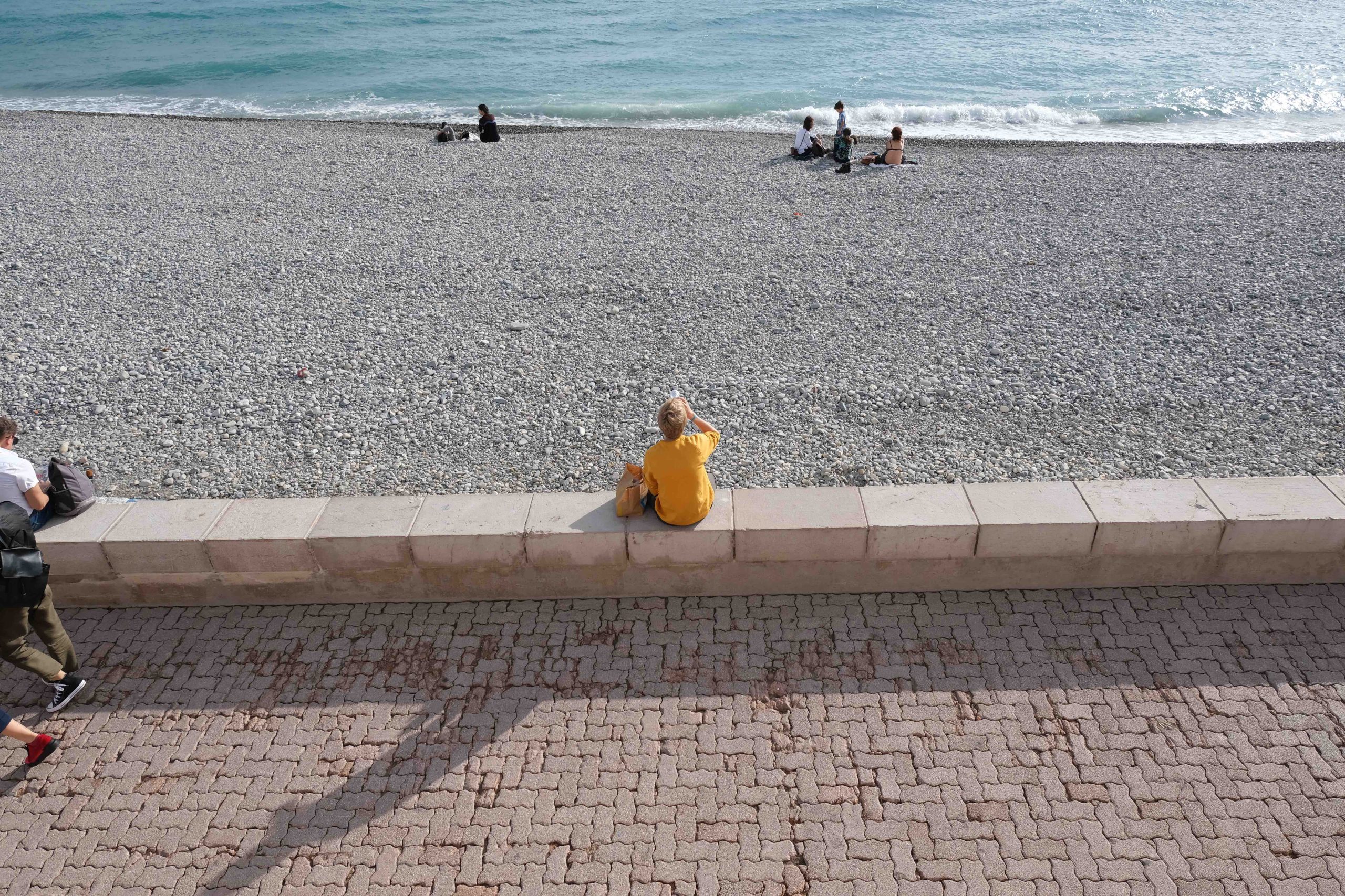 En ung man sitter vid stranden i Nice