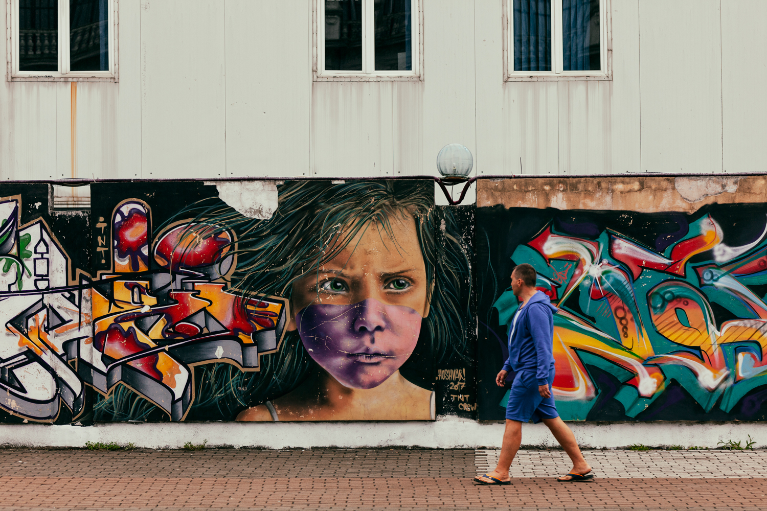 Mies ohittaa graffitiseinän